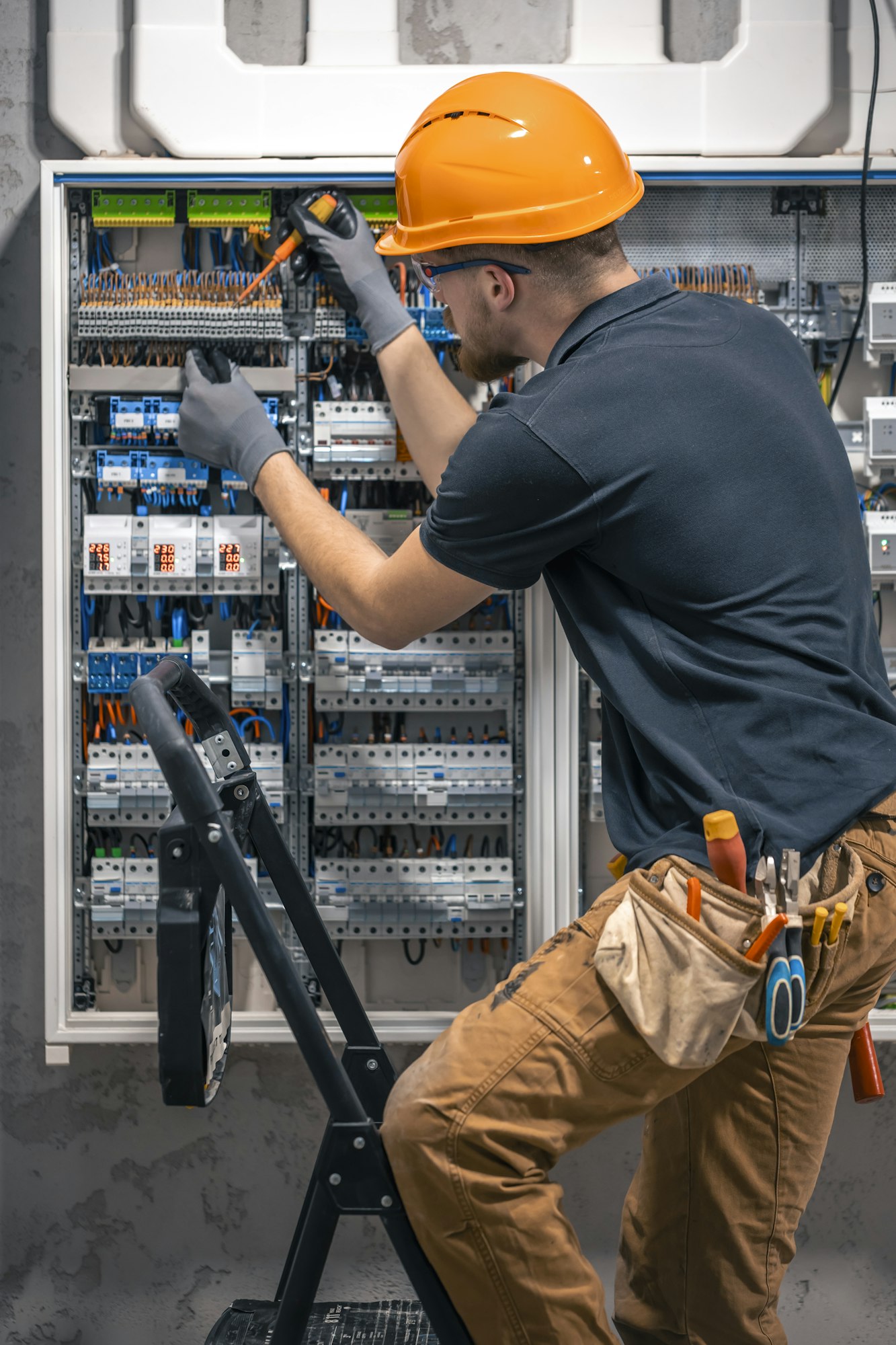 Male electrician working in a switchboard with fuses.